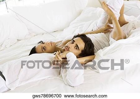 High angle view of a young couple lying on the bed View Large Photo Image Stock Image - High angle view of a young couple lying on the bed. Fotosearch