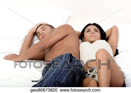 Stock Image - High angle view of a young couple lying on the bed. Fotosearch