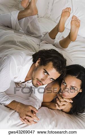High angle view of a young couple lying down on a bed View Large Photo Image Stock Photo - High angle view of a young couple lying down on a bed. Fotosearch