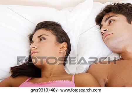 Stock Photo - High angle view of a young couple lying on the bed. Fotosearch