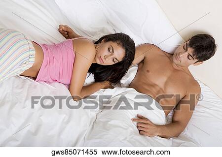 High angle view of a young couple lying on the bed View Large Photo Image Stock Photography - High angle view of a young couple lying on the bed. Fotosearch