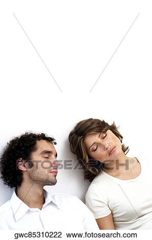 Stock Image - High angle view of a young couple sleeping against a wall. Fotosearch