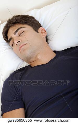 High angle view of a young man sleeping on a bed View Large Photo Image Stock Photography - High angle view of a young man sleeping on a bed. Fotosearch