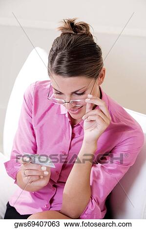 Stock Image - High angle view of a young woman looking at a credit card. Fotosearch