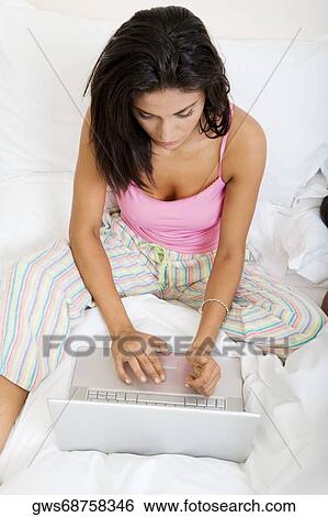 High angle view of a young woman using a laptop in bed View Large Photo Image Stock Photograph - High angle view of a young woman using a laptop in bed. Fotosearch