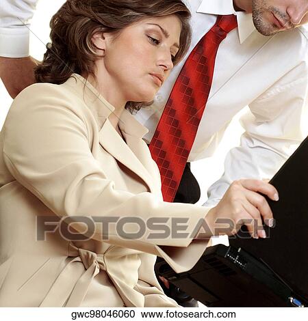 Stock Image - Low angle view of a businessman and a businesswoman looking at a laptop. Fotosearch