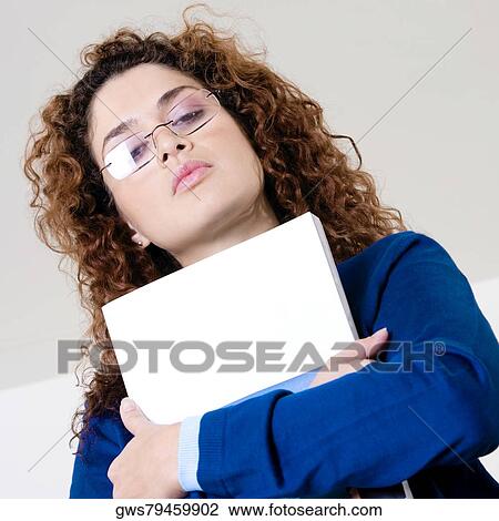 Stock Image - Low angle view of a young woman holding a file. Fotosearch