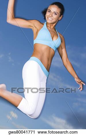 Low angle view of a young woman jumping View Large Photo Image Stock Image - Low angle view of a young woman jumping. Fotosearch