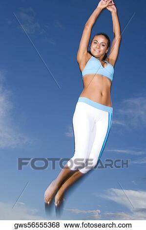 Low angle view of a young woman jumping View Large Photo Image Stock Photo - Low angle view of a young woman jumping. Fotosearch