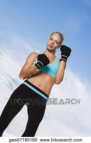 Low angle view of a young woman wearing boxing gloves View Large Photo Image Stock Image - Low angle view of a young woman wearing boxing gloves. Fotosearch