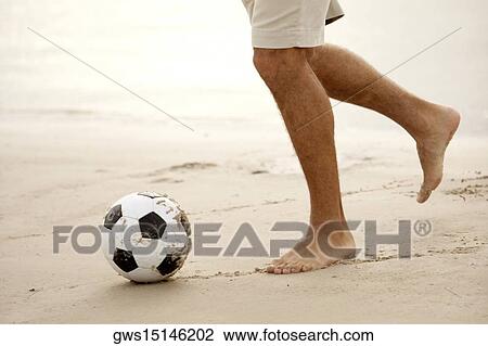 Low section view of a mid adult man playing soccer on the beach View Large Photo Image Stock Image - Low section view of a mid adult man playing soccer on the beach. Fotosearch