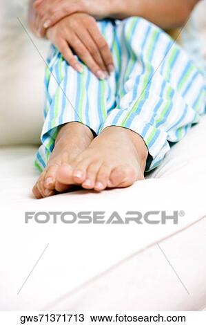 Low section view of a woman sitting on a bed View Large Photo Image Stock Image - Low section view of a woman sitting on a bed. Fotosearch