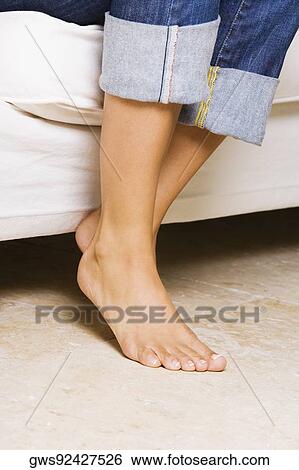 Low section view of a young woman sitting on a couch View Large Photo Image Stock Photograph - Low section view of a young woman sitting on a couch. Fotosearch