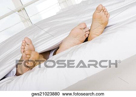 Low section view of the feet of two people on a bed View Large Photo Image Stock Image - Low section view of the feet of two people on a bed. Fotosearch