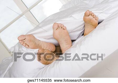 Low section view of the feet of two people on a bed View Large Photo Image Stock Photography - Low section view of the feet of two people on a bed. Fotosearch