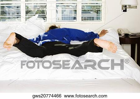 Mid adult man jumping on the bed View Large Photo Image Stock Photograph - Mid adult man jumping on the bed. Fotosearch