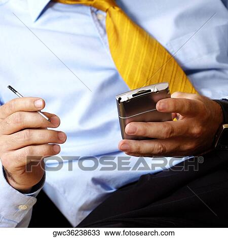 Stock Image - Mid section view of a businessman holding a personal data assistant. Fotosearch