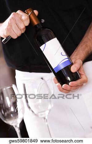 Mid section view of a man opening the cork of a wine bottle View Large Photo Image Stock Photo - Mid section view of a man opening the cork of a wine bottle. Fotosearch