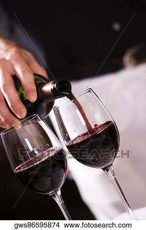 Mid section view of a man pouring red wine into a wineglass View Large Photo Image Picture - Mid section view of a man pouring red wine into a wineglass. Fotosearch