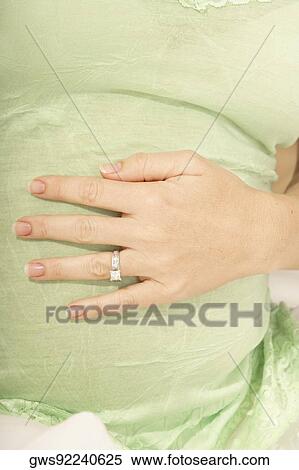 Mid section view of a pregnant mid adult woman touching her abdomen View Large Photo Image Stock Photography - Mid section view of a pregnant mid adult woman touching her abdomen. Fotosearch