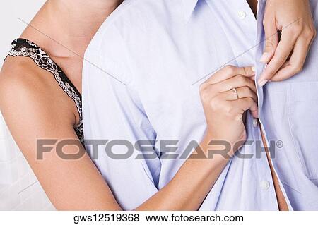 Stock Photo - Mid section view of a woman buttoning a man's shirt from behind. Fotosearch