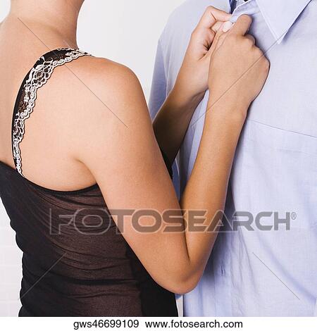 Mid section view of a woman buttoning the shirt of a man View Large Photo Image Stock Photo - Mid section view of a woman buttoning the shirt of a man. Fotosearch