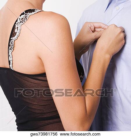 Mid section view of a woman buttoning the shirt of a man View Large Photo Image Stock Photograph - Mid section view of a woman buttoning the shirt of a man. Fotosearch