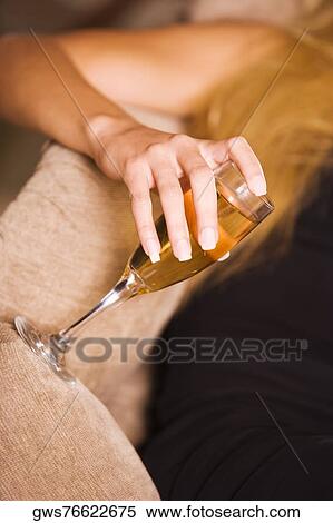 Mid section view of a woman holding a champagne flute View Large Photo Image Stock Photography - Mid section view of a woman holding a champagne flute. Fotosearch