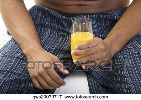 Mid section view of a young man holding a glass of orange juice View Large Photo Image Stock Photo - Mid section view of a young man holding a glass of orange juice. Fotosearch