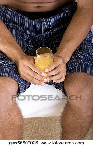 Mid section view of a young man holding a glass of orange juice View Large Photo Image Stock Photograph - Mid section view of a young man holding a glass of orange juice. Fotosearch