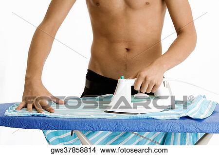 Mid section view of a young man ironing his shirt View Large Photo Image Picture - Mid section view of a young man ironing his shirt. Fotosearch