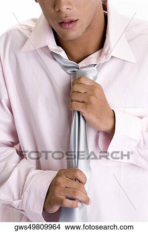 Mid section view of a young man adjusting his tie View Large Photo Image Picture - Mid section view of a young man adjusting his tie. Fotosearch