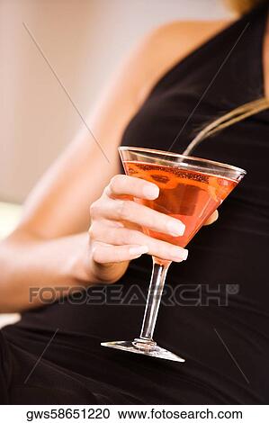 Mid section view of a young woman holding a martini glass View Large Photo Image Stock Image - Mid section view of a young woman holding a martini glass. Fotosearch