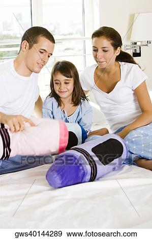 Parents and their daughter sitting on the bed View Large Photo Image Stock Photo - Parents and their daughter sitting on the bed. Fotosearch