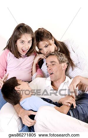 Stock Photography - Parents sitting with their son and daughter on an armchair. Fotosearch