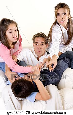 Parents with their son and daughter pressing buttons on a remote control View Large Photo Image Stock Photo - Parents with their son and daughter pressing buttons on a remote control. Fotosearch