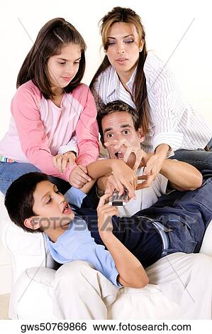 Parents with their son and daughter pressing buttons on a remote control View Large Photo Image Stock Photograph - Parents with their son and daughter pressing buttons on a remote control. Fotosearch