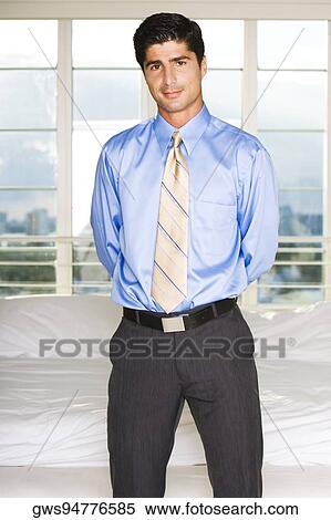 Stock Photography - Portrait of a businessman standing with his hands behind his back. Fotosearch