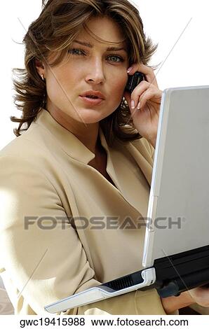 Stock Photo - Portrait of a businesswoman holding a laptop while talking on a mobile phone. Fotosearch