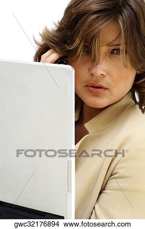 Picture - Portrait of a businesswoman talking on a mobile phone in front of a laptop. Fotosearch