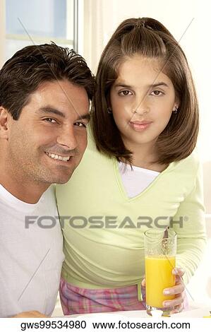 Portrait of a girl sitting and holding a glass of orange juice with her father View Large Photo Image Stock Image - Portrait of a girl sitting and holding a glass of orange juice with her father. Fotosearch