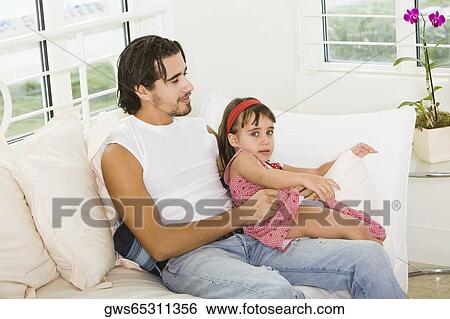 Stock Photograph - Portrait of a girl sitting on her father's lap. Fotosearch