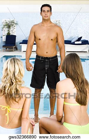 Portrait of a mid adult man standing in front of two young women at the poolside View Large Photo Image Stock Image - Portrait of a mid adult man standing in front of two young women at the poolside. Fotosearch