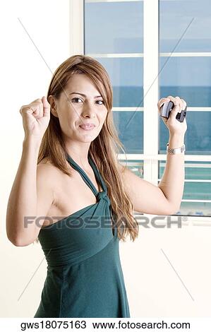 Stock Image - Portrait of a mid adult woman holding a mobile phone. Fotosearch