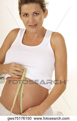 Portrait of a pregnant woman measuring her abdomen with a measuring tape View Large Photo Image Stock Image - Portrait of a pregnant woman measuring her abdomen with a measuring tape. Fotosearch