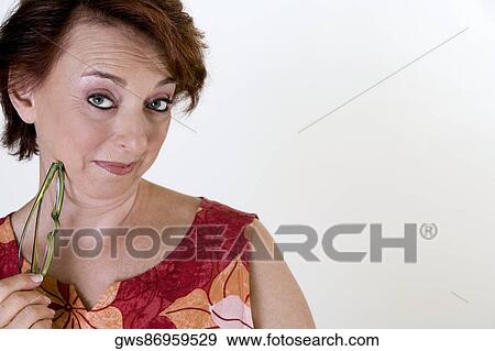 Stock Photo - Portrait of a senior woman holding eyeglasses. Fotosearch