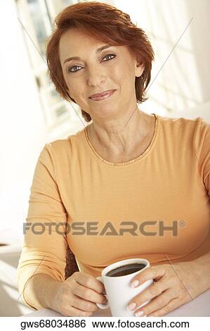 Portrait of a senior woman seated at a table with a cup of coffee View Large Photo Image Stock Photograph - Portrait of a senior woman seated at a table with a cup of coffee. Fotosearch