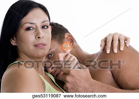 Stock Photo - Portrait of a young couple embracing each other holding a condom. Fotosearch