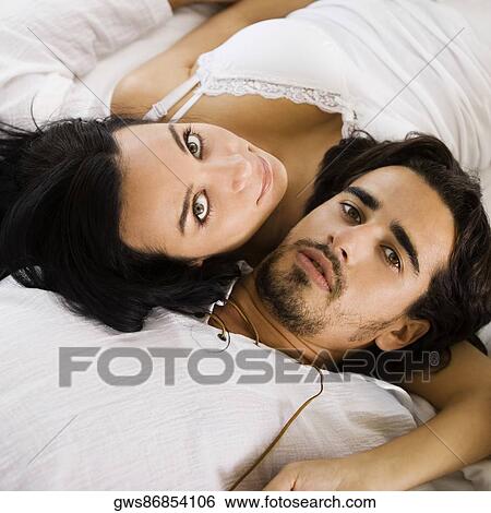 Stock Photograph - Portrait of a young couple lying on the bed. Fotosearch