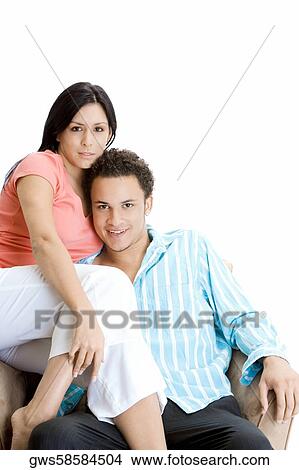 Portrait of a young couple sitting on an armchair View Large Photo Image Picture - Portrait of a young couple sitting on an armchair. Fotosearch